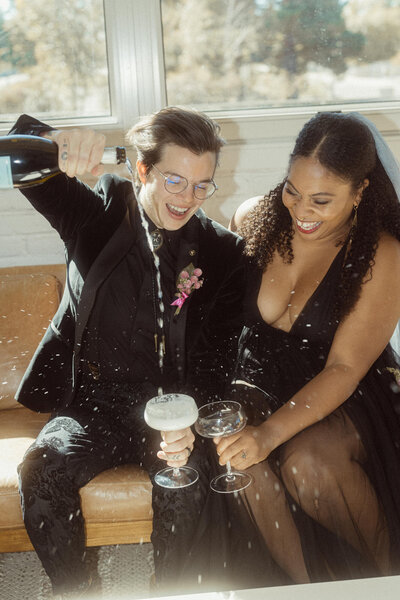 A couple sitting together as one pours them champagne.