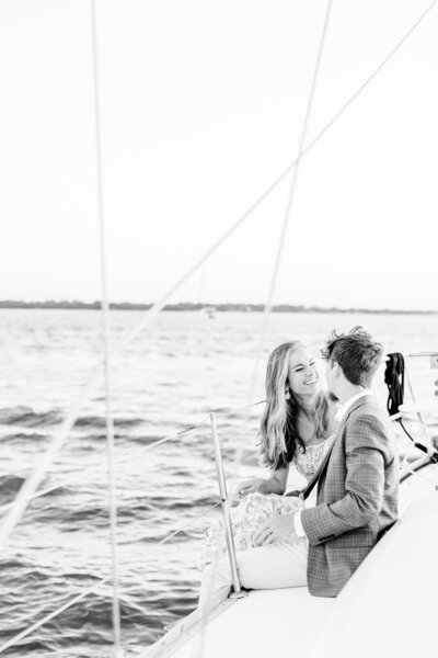 engaged couple smiling on a sailboat in charleston