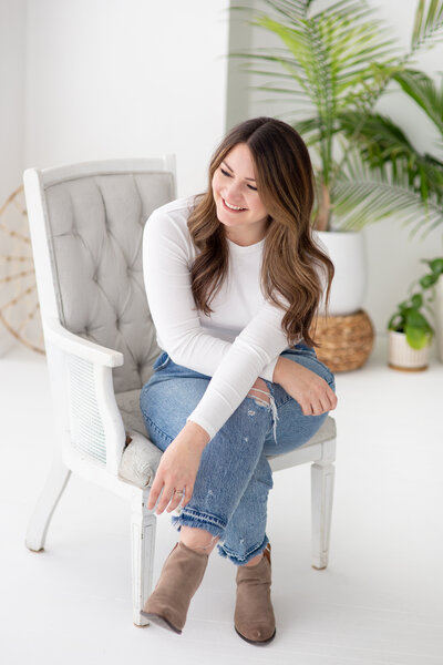 Woman in studio in grey chair laughing and showing her beautiful flowing hair