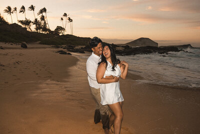 couple on beach laughing in front of sunset