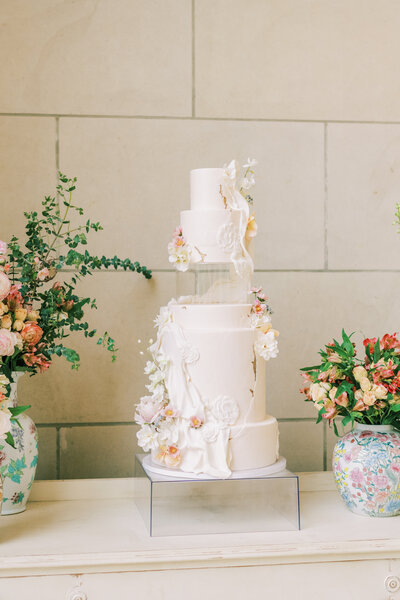 Large multi tier white wedding cake on a stand decorated with florals