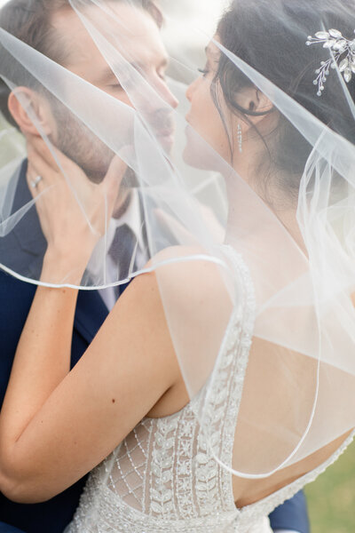 Bride and Groom kissing under veil