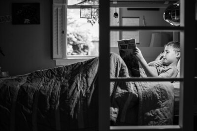 A boy reading a book in his bed