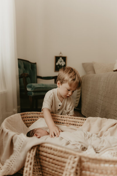 New mother cradling newborn baby while sitting in nursery rocking chair, captured during lifestyle newborn session – Morristown, NJ