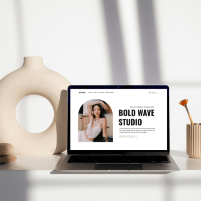 Laptop displaying thewebsite design for social media managers on a minimalist desk with decorative items,