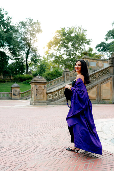 Graduation portrait of a student holding cap and wearing gown at Bethesda Terrace in Central Park.