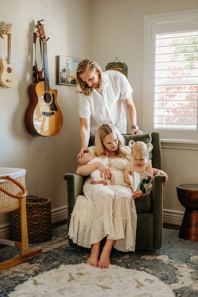 mom in nursery holding newborn son and toddler daughter. dad is over them looking down fondly
