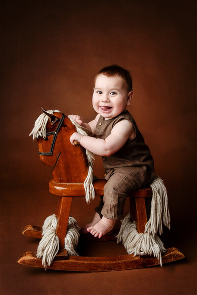Little boy sitting on a wooden rocker horse