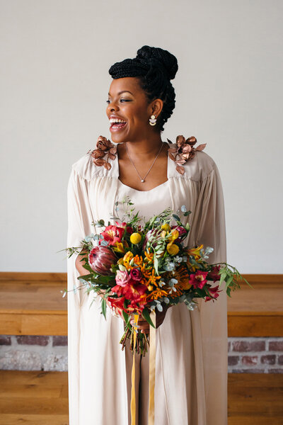 Plymouth based Bride wearing jumpsuit and a cape with colourful bouquet