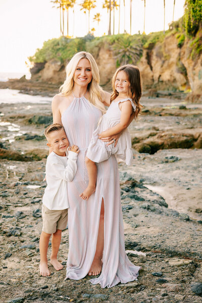 Mom holding daughter on hip and standing next to son at Laguna Beach family session by Ashley Nicole Photography.