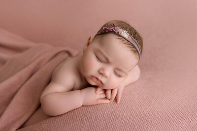 pregnant woman standing in a white gown, in a forest setting holding her pregnant belly looking down in awe.