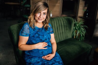 Pregnant lady in blue dress smiling at camera, sitting on green couch inside Northside Wines, Northcote. 