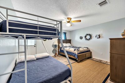 Bedroom with bunk beds and queen bed in with half bath at this 3-bedroom, 2.5 bathroom rural vacation rental house just minutes outside of downtown Waco, TX.
