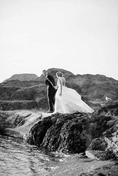 Black and white image of a married couple walking along the coast taken by Cornwall Wedding Photographer and Devon Wedding Photographer Liberty Pearl