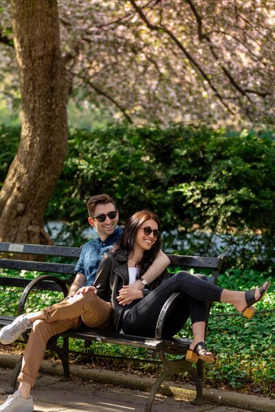 A couple sitting on a park bench together holding hands.