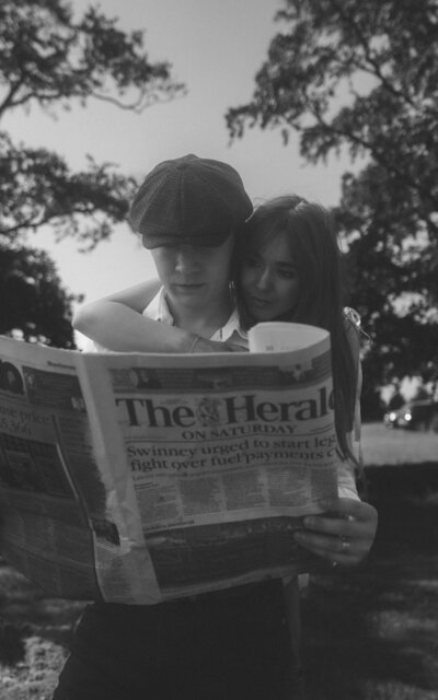 A classic black and white photo of a couple with vintage vibes, sharing a moment while reading a newspaper