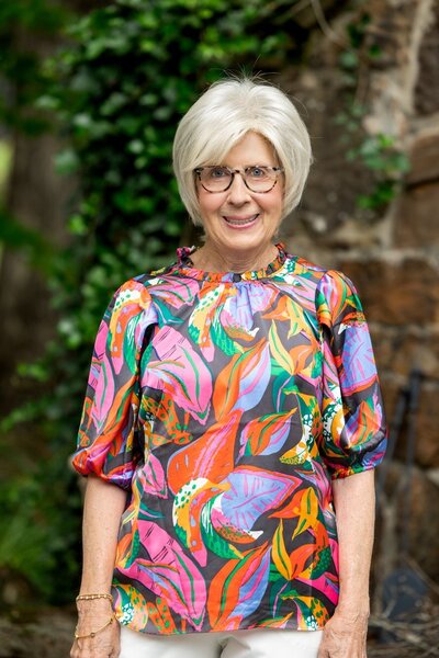 Portrait of Mrs. Munsey smiling in a colorful floral blouse, representing the family behind Better Lawns and Gardens in Little Rock, Arkansas.
