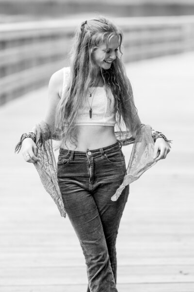 Senior girl dances on a bridge.