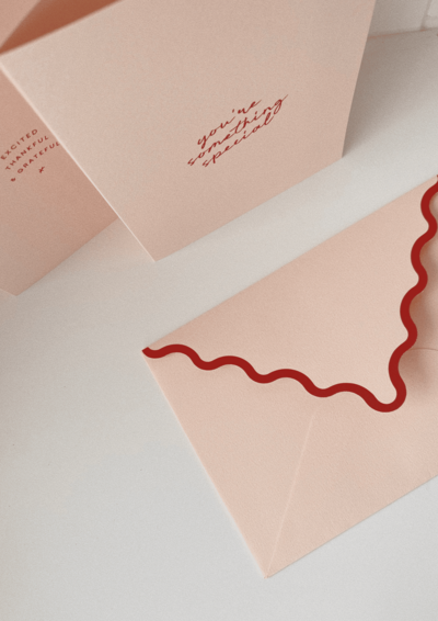 A close-up of a pink greeting card with the message "You're Something Special" written in red script. The card is lying on a white surface next to a pink envelope with a scalloped red border.