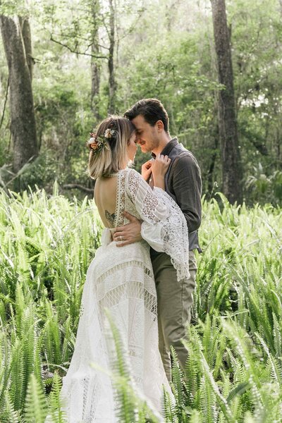 Couple forehead to forehead in a field of ferns