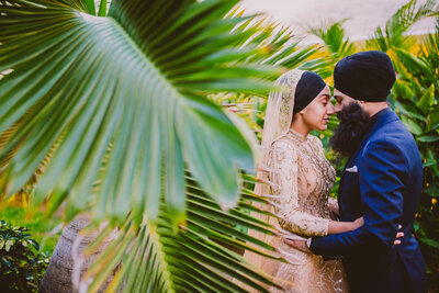 Sikh amritdhari couple embrace in front of palm trees at the moon palace resort in cancun mexico