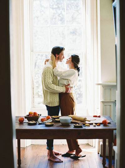 Couple almost kiss while making apple pies during their styled autumn engagement session from Willow and Oak