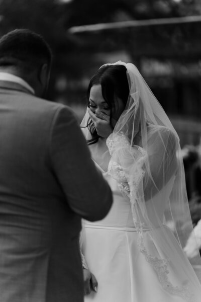 A black and white photo of a wedding couple walking. Bride is walking barefoot and groom is holding her shoes. 