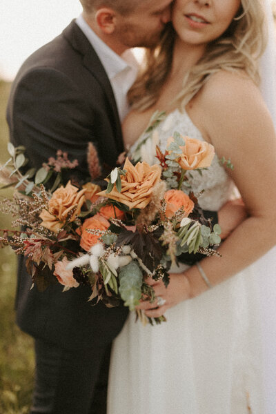 bride and groom holding flower bouquet