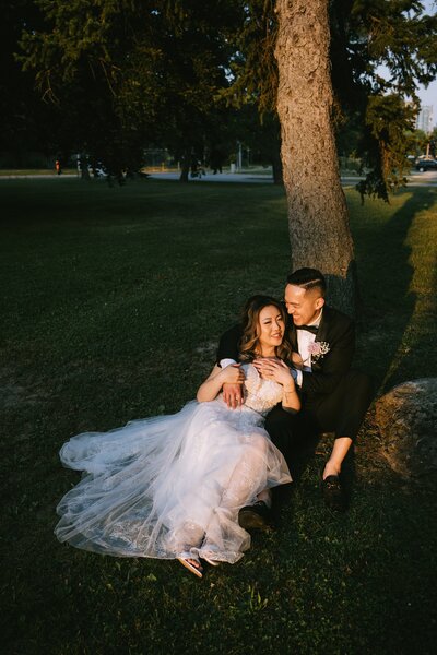 Bride and groom sitting under a tree