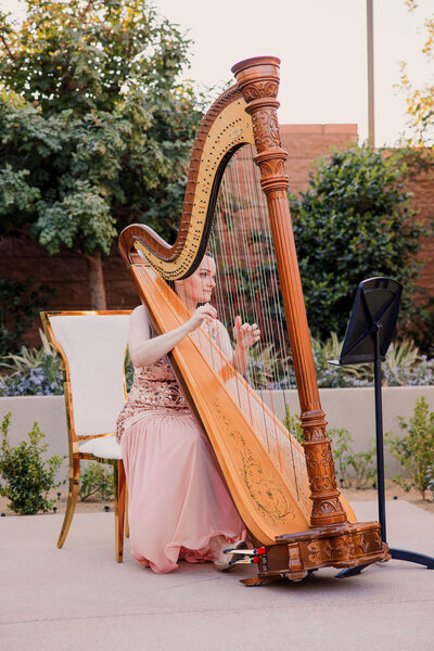Wedding harpist in a pink dress at an outdoor wedding ceremony at DragonRidge Country Club in Henderson, Nevada