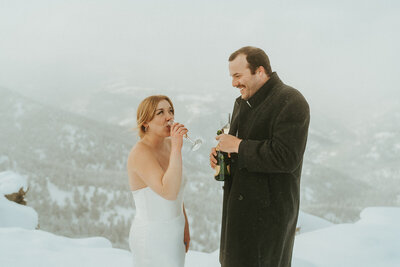 During winter elopement in Colorado,  bride and groom drink some champagne to celebrate after reading vows