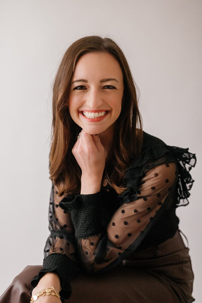 Headshot of woman in a black top resting her chin on her hand