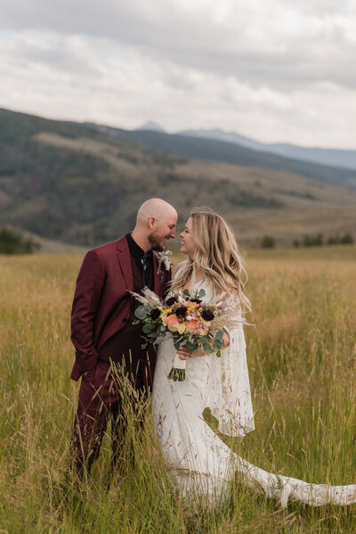 couple in a grassy field with mountains after their wedding ceremony in Colorado