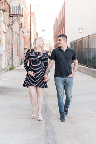 pregnant couple walking down the street in downtown area