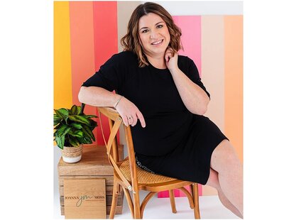 woman in a black dress sitting in a chair with a colorful striped background