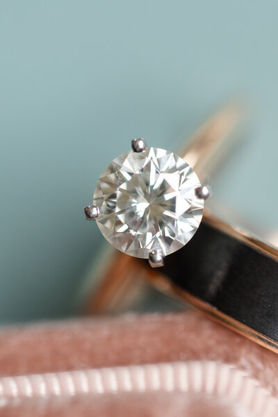 Close up of engagement ring resting against groom's wedding band