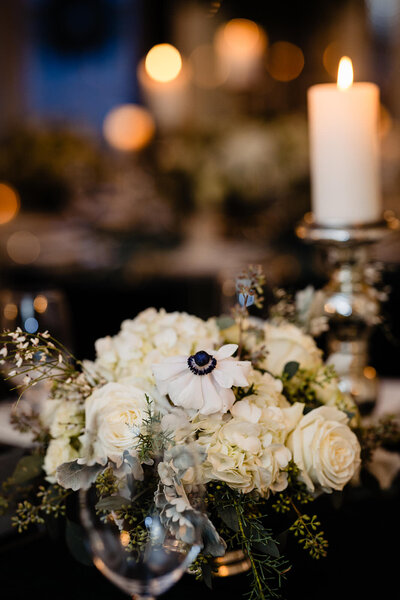 A close up view of a bouquet of flowers on a candlelit table setting at a lord thompson manor wedding