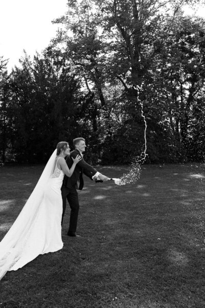 Bruidspaar popt champagne op bruiloft, vastgelegd door trouwfotograaf in Utrecht Linda Photography