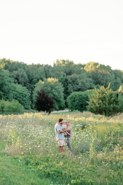 Family standing in a field of flowers, snuggling.