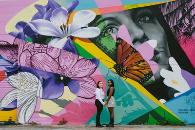 Queer Couple posing in front of a mural during their New York Engagement photo session