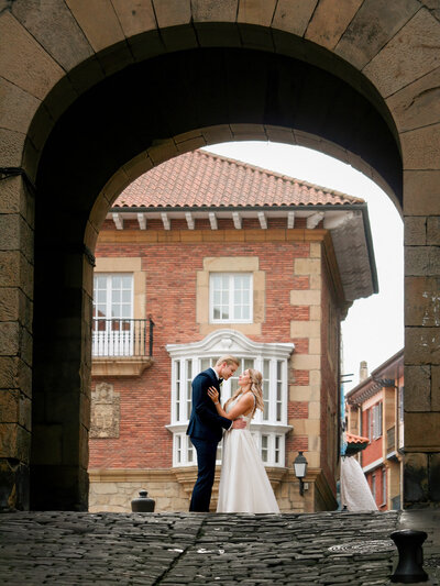 Captivating photograph of a bride and groom standing under an arch in Pamplona, adding a touch of Spanish charm and architectural elegance to their wedding day.