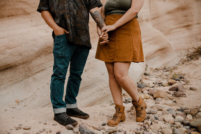 couple holds hand in front of rock formation