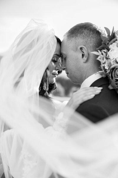Up close moment of bride and groom with bride's veil artfully pulled over to create soft image