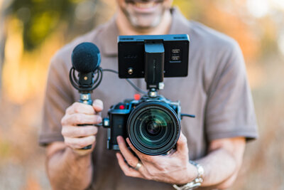 Brian Sellers, a destination wedding videographer based in Williamsburg, VA, holding a camera he uses to craft authentic cinematic wedding films for brides and wedding couples