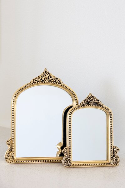Two ornate gold oval mirrors on black easel stand