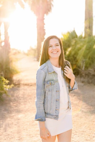 Sandra Yvonne, systems strategist for wedding photographers, smiling outdoors in a light denim jacket, helping photographers build simple HoneyBook workflows that support chronic illness.