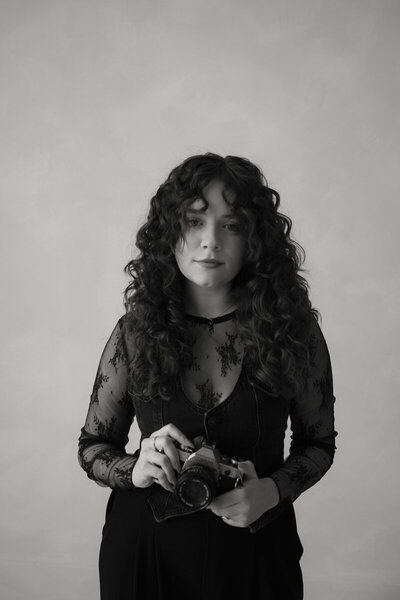 woman sitting on a couch and smiling holding a camera
