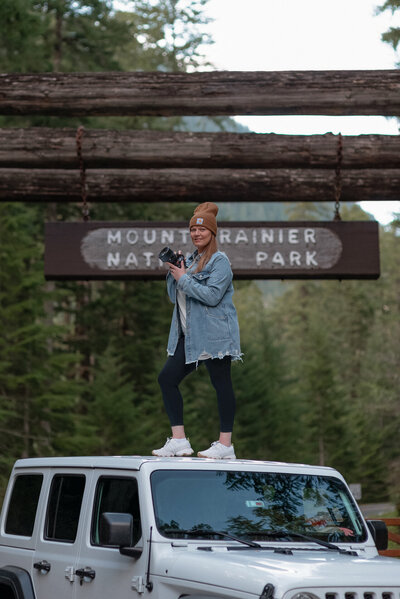 girl outside with camera standing on jeep