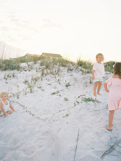 Three little kids running around in the sand on the beach
