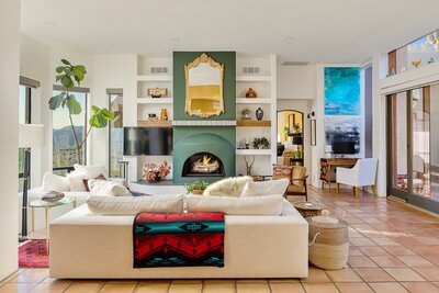 Colorful living room in Cave Creek with saltillo floors, a green fireplace, and mountain views.